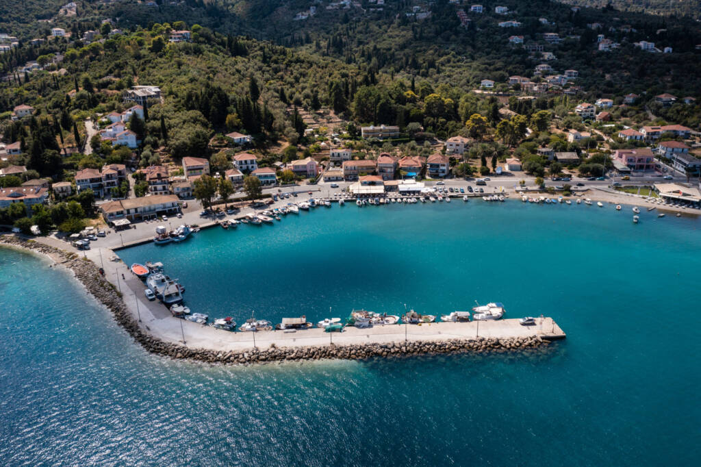 A serene coastal view of Lygia, Lefkas, showcasing azure waters and the port of the town, where boats reside.