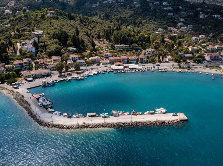 A serene coastal view of Lygia, Lefkas, showcasing azure waters and the port of the town, where boats reside.